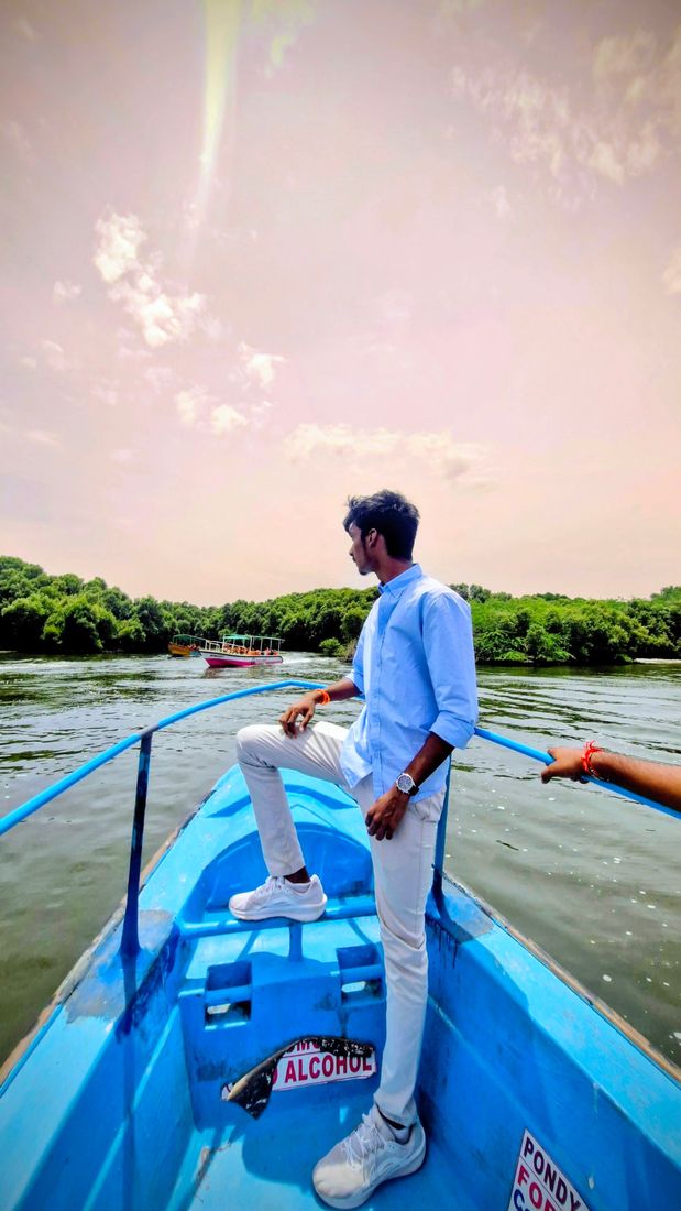 Nuthan standing at the bow of a blue boat